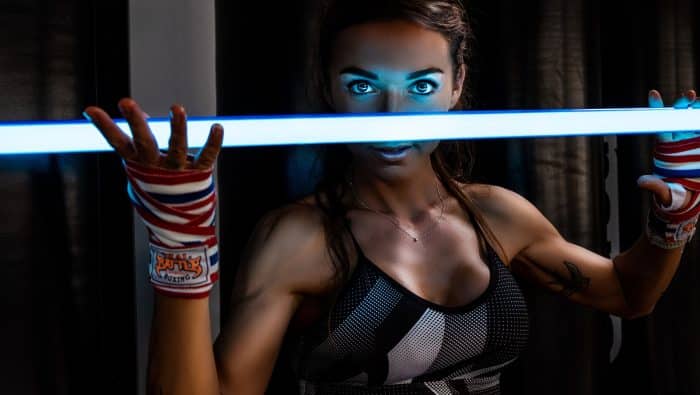 a woman with blue makeup holding a light saber