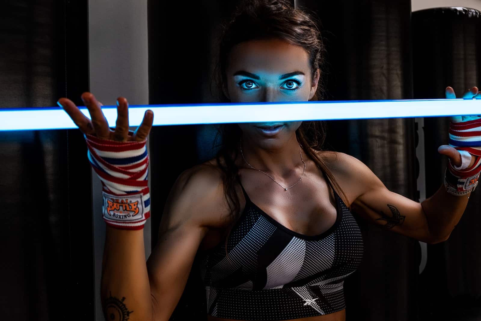 a woman with blue makeup holding a light saber
