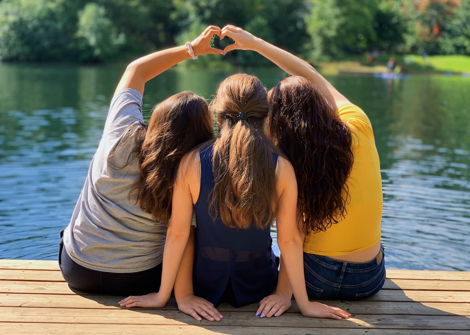 2 women sitting on wooden dock during daytime