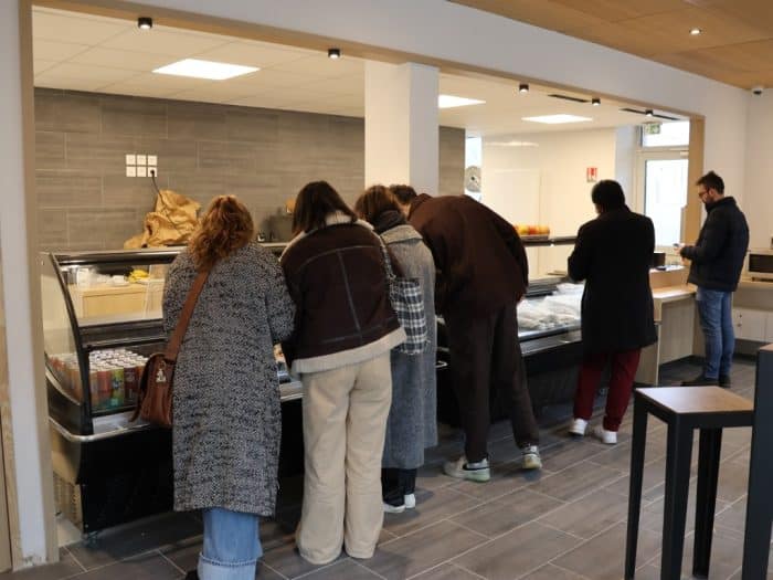 étudiantes et étudiants regardant la vitrine d'une cafétéria avant de commander