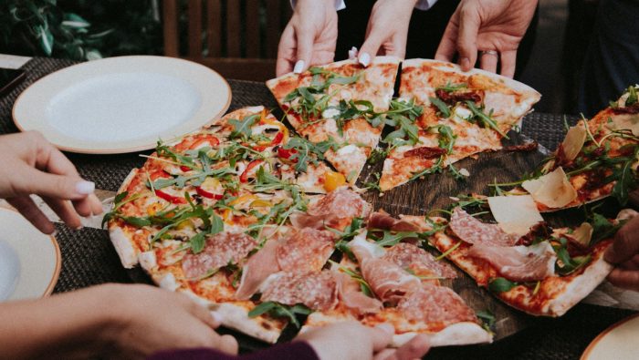 person holding pizza on white ceramic plate