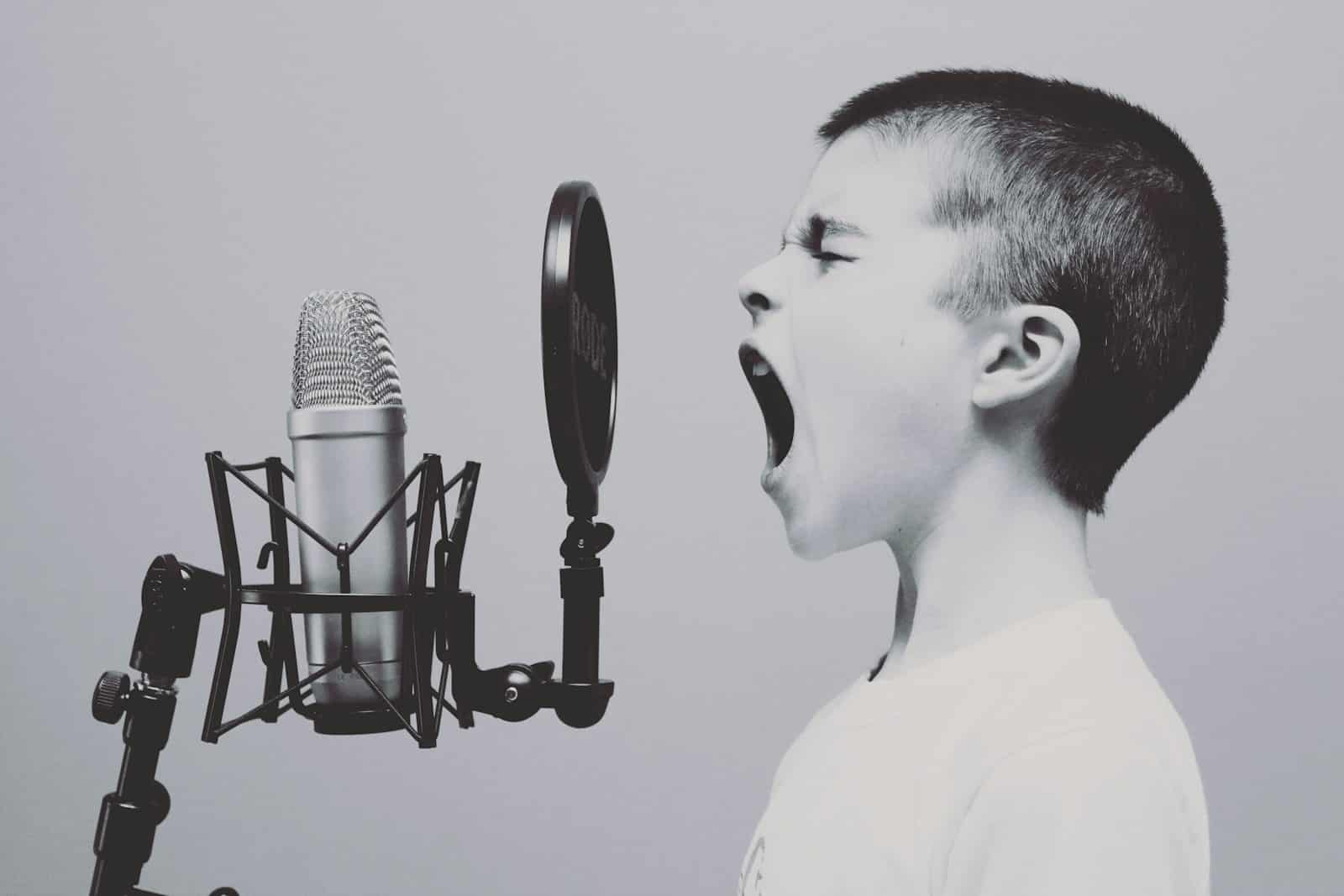 Photo by Jason Rosewell boy singing on microphone with pop filter