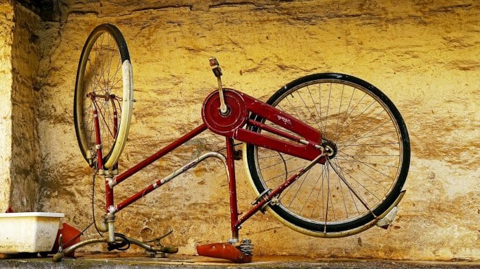 Atelier de réparation de vélo 1 A vintage red bicycle frame against a textured wall.